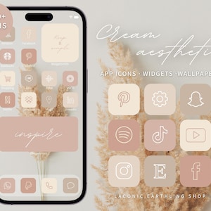 May include: A phone screen mockup with a cream aesthetic theme. The phone screen displays a grid of app icons with a minimalist design. The icons are in shades of beige and white with a light brown background. The text "Cream aesthetic" is displayed at the top of the image. The text "APP ICONS - WIDGETS - WALLPAPERS" is displayed below the cream aesthetic text. The text "LACONIC EARTHLING SHOP" is displayed at the bottom of the image.