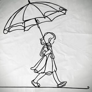 May include: A black wire sculpture of a person walking with an umbrella. The sculpture is made of thin wire and is very detailed.