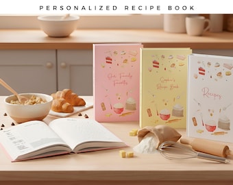 May include: Three hardcover recipe books in pink, yellow, and white, each featuring watercolor illustrations of baking ingredients and text. The pink book reads Our Family Favorites, the yellow book reads Sophie's Recipe Book, and the white book reads Recipes.