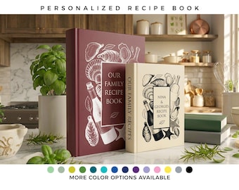 May include: Two hardcover recipe books standing upright. The larger book is deep red with white line art of shells and a wine bottle, labeled "OUR FAMILY RECIPE BOOK." The smaller book is cream with black line art, labeled "NINA & GEORGES RECIPE BOOK."