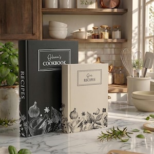 May include: Two hardcover recipe books, one black and one cream, featuring white and black line art illustrations of herbs and a mortar and pestle. The black book is titled Olivia's COOKBOOK and the cream book is titled Our RECIPES.