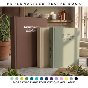 Op de afbeelding: Drie receptenboeken met harde kaft in bruin, crème en saliegroen. Het bruine boek bevat de tekst Grandma's Kitchen. Het saliegroene boek bevat de tekst Our Family Recipes en de rug van het crèmekleurige boek bevat de tekst MADE WITH LOVE.