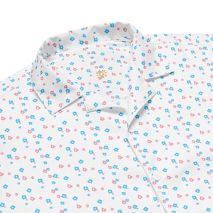 May include: White shirt with a floral pattern of small blue and pink flowers. The collar has a small embroidered sun design. The shirt is made of a lightweight fabric, suitable for warmer weather.
