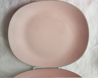 Könnte beinhalten: Ein Satz rosa Keramik-Dinnerteller mit leicht strukturierter Oberfläche. Die Teller sind übereinander gestapelt.