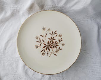 Op de afbeelding: Een wit keramiek dinerbord met een gouden rand en een bruin en blauw bloemenontwerp.