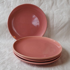 Puede incluir: Cuatro platos de cena de cerámica rosa apilados uno encima del otro.