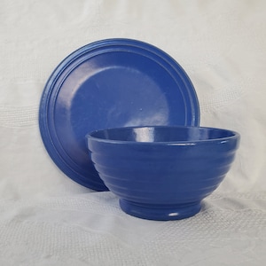 May include: A set of blue ceramic dishes, a bowl and a plate, both with a simple, rounded design.