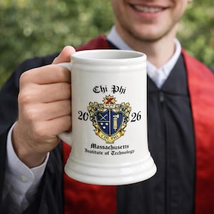 May include: A white ceramic beer stein with a handle, featuring the text "Chi Phi" and a crest with the years "2026" and "1824". The words "Massachusetts Institute of Technology" are also printed on the stein.