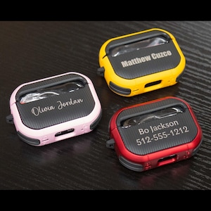 May include: Three personalized AirPod cases in pink, yellow, and red. The pink case says "Olivia Jordan", the yellow case says "Matthew Cuzco", and the red case says "Bo Jackson 512-555-1212".