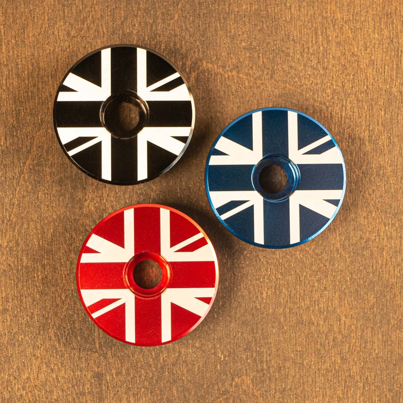 May include: Three circular objects with a Union Jack design. One is black with white accents, another is blue with white accents, and the third is red with white accents. Each has a central hole.