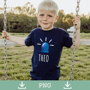Puede incluir: Un niño pequeño con una camiseta azul marino con un gráfico de sirena azul y el nombre "THEO" en blanco. El niño sonríe y sostiene una cadena de columpio en un entorno exterior cubierto de hierba.