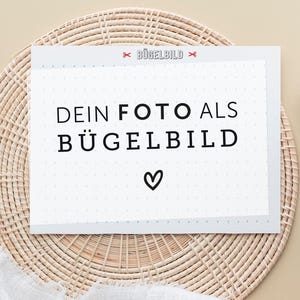 Könnte beinhalten: Eine rechteckige weiße Karte mit hellgrauem Rastermuster, die mittig den schwarzen Text "DEIN FOTO ALS BÜGELBILD" zeigt, darunter ein kleines schwarzes Herzsymbol sowie oben den roten Text "BÜGELBILD", eingerahmt von zwei roten Scherensymbolen.