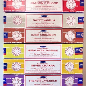 Może przedstawiać: Stos sześciu prostokątnych pudełek kadzidełek Satya Nag Champa w kolorach czerwonym, beżowym, brązowym, jasnym zielonym, żółtym i fioletowym. Każde pudełko zawiera napis Dragon's Blood, Sweet Vanilla, Dark Cinnamon, Himalayan Jasmine, Seven Chakra lub French Lavender.