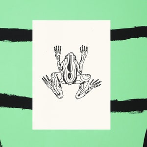 Puede incluir: Un dibujo en blanco y negro de una rana con intrincados detalles en su cuerpo y extremidades. La rana está sentada sobre un fondo blanco.
