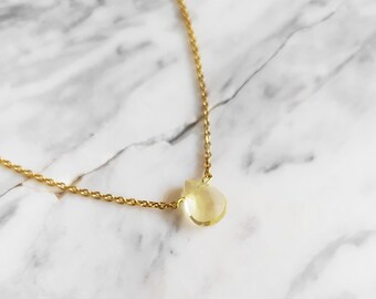 Puede incluir: Un delicado collar de cadena dorada con un solo colgante de piedra preciosa amarilla en forma de lágrima.