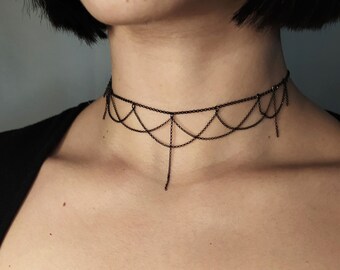 May include: A black choker necklace with a delicate chain design and dangling chain accents.