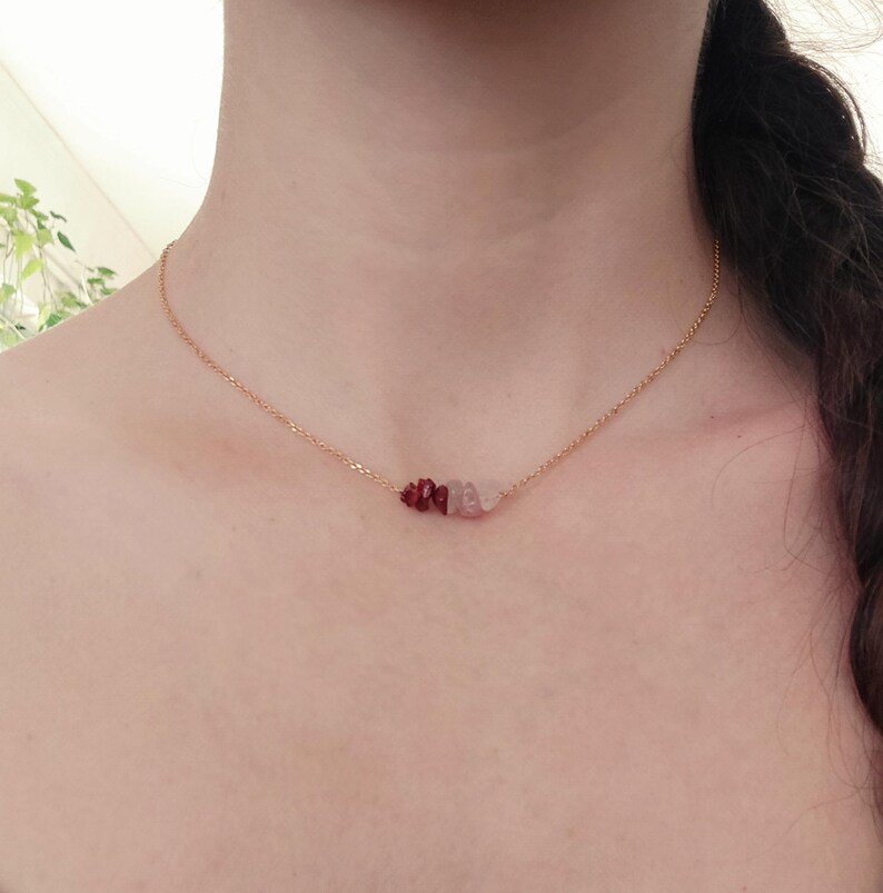 May include: A gold chain necklace with a small cluster of red and pink stones.