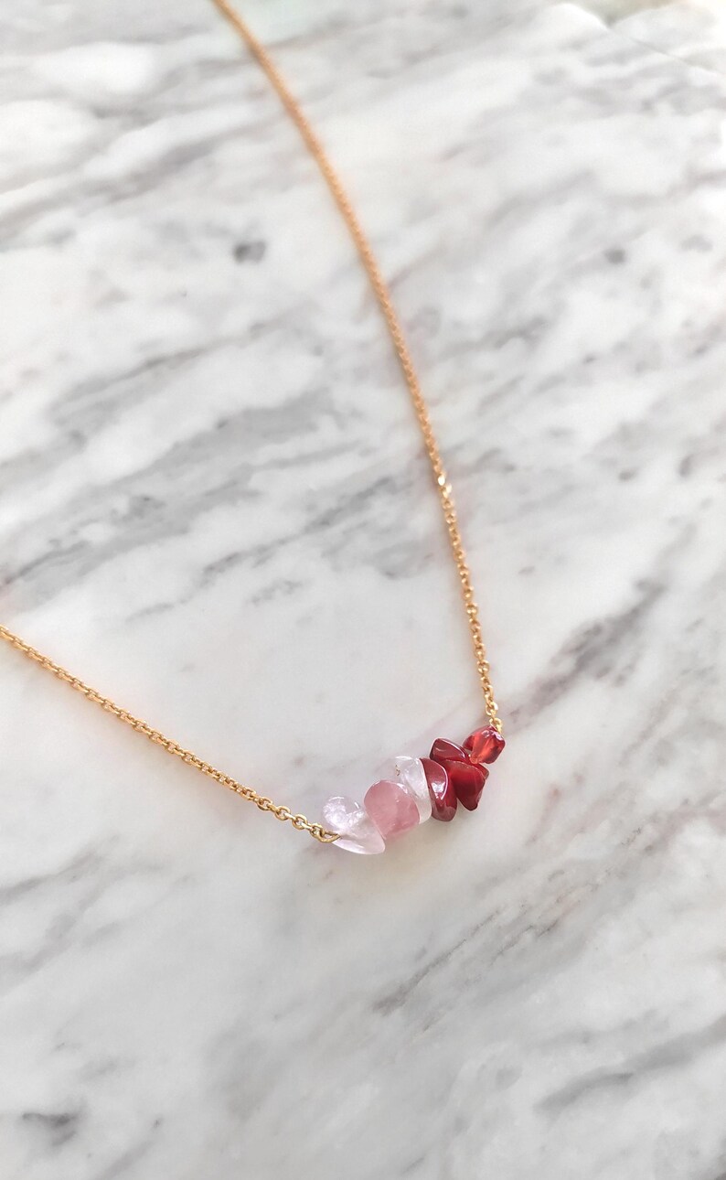 May include: A gold chain necklace with a cluster of pink and red gemstone chips.