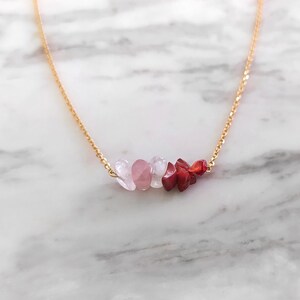 May include: A gold chain necklace with a cluster of pink and red gemstone beads.