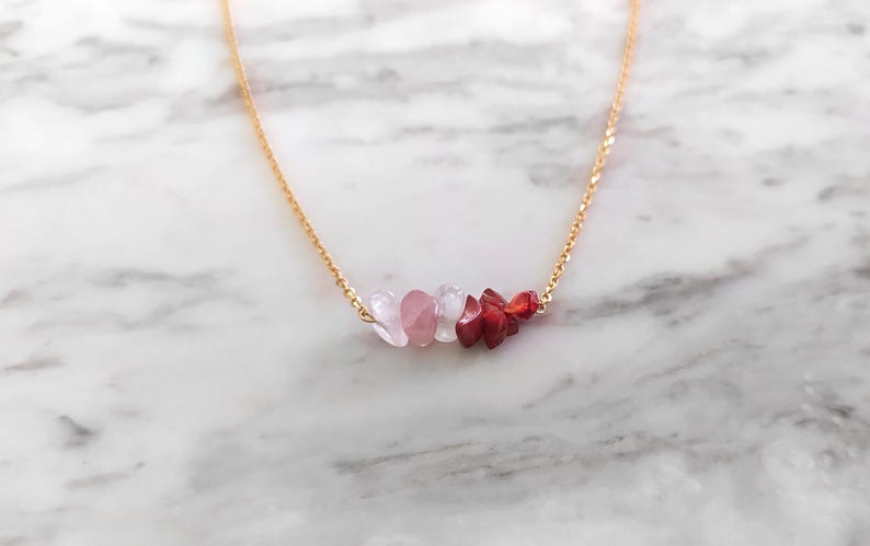 May include: A gold chain necklace with a cluster of pink and red gemstone beads.