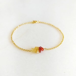 May include: A gold chain bracelet with a small cluster of orange, red, and yellow gemstones.