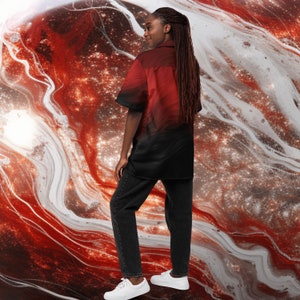 Op de afbeelding: Een persoon draagt een rood en zwart knoopshirt met een galaxy print. Het shirt heeft een korte mouw en een kraag. De persoon draagt een zwarte broek en witte sneakers.