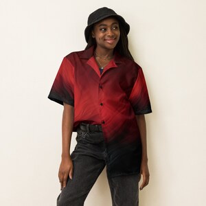 Op de afbeelding: Een persoon draagt ​​een rood-zwart geprint overhemd met knopen, een zwarte bucket hat en een zwarte jeans.