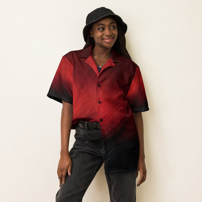 Op de afbeelding: Een persoon draagt ​​een rood-zwart geprint overhemd met knopen, een zwarte bucket hat en een zwarte jeans.