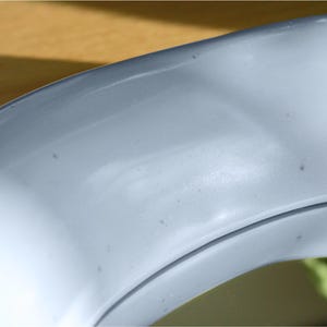 May include: Close-up of a curved, light blue object with a smooth, glossy surface. The object has a subtle sheen and appears to be made of a solid material. The image is well-lit, highlighting the curves and contours of the object.