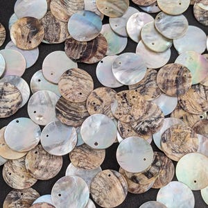 Puede incluir: Una colección de cuentas redondas de concha de nácar iridiscente. Las cuentas varían en color, con tonos de blanco, marrón y gris. Cada cuenta tiene un pequeño agujero para ensartar. Estas cuentas de concha natural son ideales para la fabricación de joyas y manualidades.