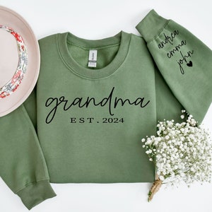 May include: Green sweatshirt with the text "grandma est. 2024" on the front and the names "andrea emma john" on the sleeve.