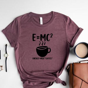 May include: A maroon t-shirt with a black graphic that says "E=MC2" with a coffee cup and the text "ENERGY=MILK*COFFEE".