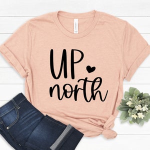 May include: A peach-colored t-shirt with the text "UP north" in black lettering and a small black heart.