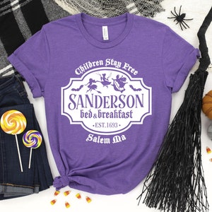 May include: Purple t-shirt with a white graphic of a sign that reads "Children Stay Free Sanderson Bed & Breakfast Est. 1693 Salem Ma".
