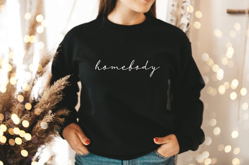 May include: Black sweatshirt with the text "homebody" written in white cursive script.