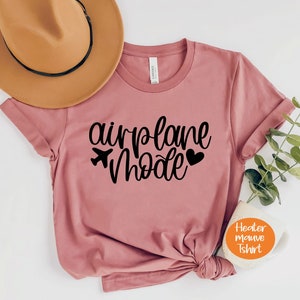 May include: A heather mauve t-shirt with the text "airplane mode" in black lettering. The text includes a small airplane icon and a heart.