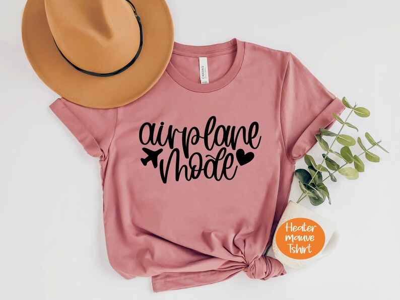 May include: A heather mauve t-shirt with the text "airplane mode" in black lettering. The text includes a small airplane icon and a heart.
