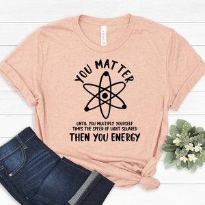 May include: A peach-coloured t-shirt with a black atom graphic and the text "You Matter Until You Multiply Yourself Times The Speed Of Light Squared Then You Energy".