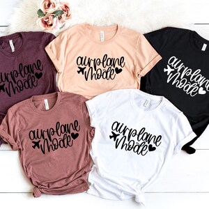 May include: Five t-shirts with the text "airplane mode" in black lettering with a small airplane icon and heart. The shirts are in various colors including maroon, peach, white, and black.