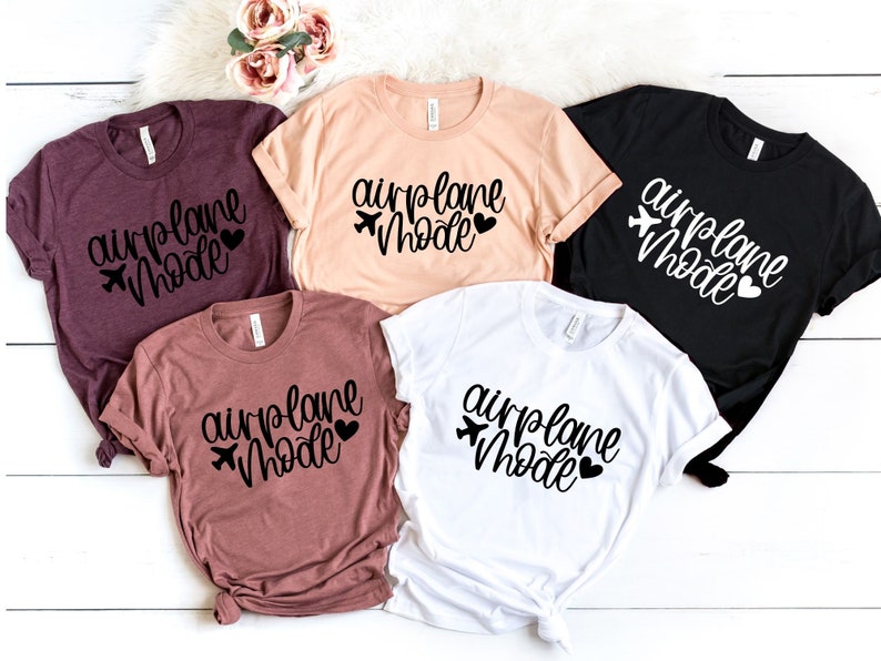 May include: Five t-shirts with the text "airplane mode" in black lettering with a small airplane icon and heart. The shirts are in various colors including maroon, peach, white, and black.