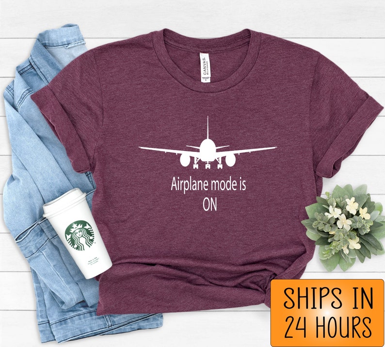 May include: A maroon t-shirt with a white airplane silhouette and the text "Airplane mode is ON".