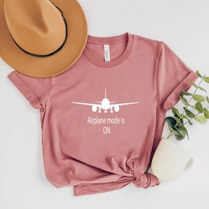 May include: A pink t-shirt with a white airplane graphic and the text "Airplane mode is ON".