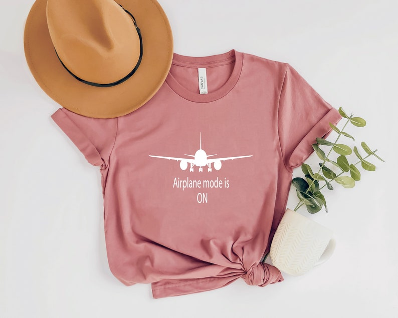 May include: A pink t-shirt with a white airplane graphic and the text "Airplane mode is ON".