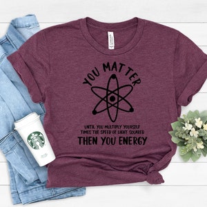 May include: A maroon t-shirt with a black atom graphic and the text "You Matter Until You Multiply Yourself Times The Speed Of Light Squared Then You Energy".