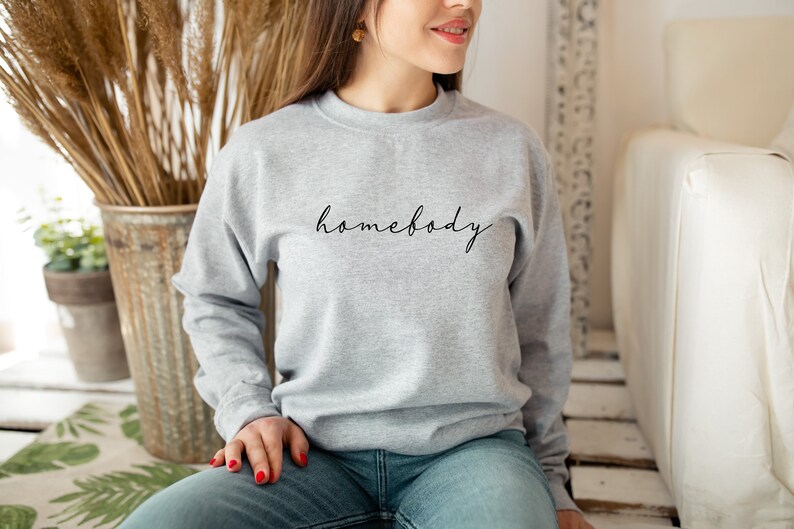 May include: A gray sweatshirt with the text "homebody" written in black cursive on the front.