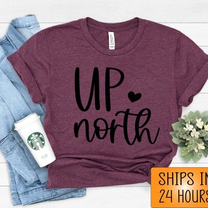 May include: A maroon t-shirt with the text "UP north" in black lettering with a small heart between the words.