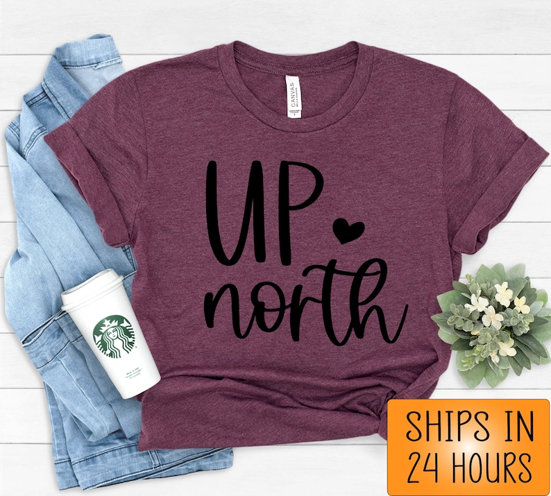 May include: A maroon t-shirt with the text "UP north" in black lettering with a small heart between the words.