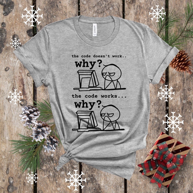 May include: Gray t-shirt with a black and white illustration of a person at a computer. The text on the shirt reads: "the code doesn't work... why? the code works... why?"