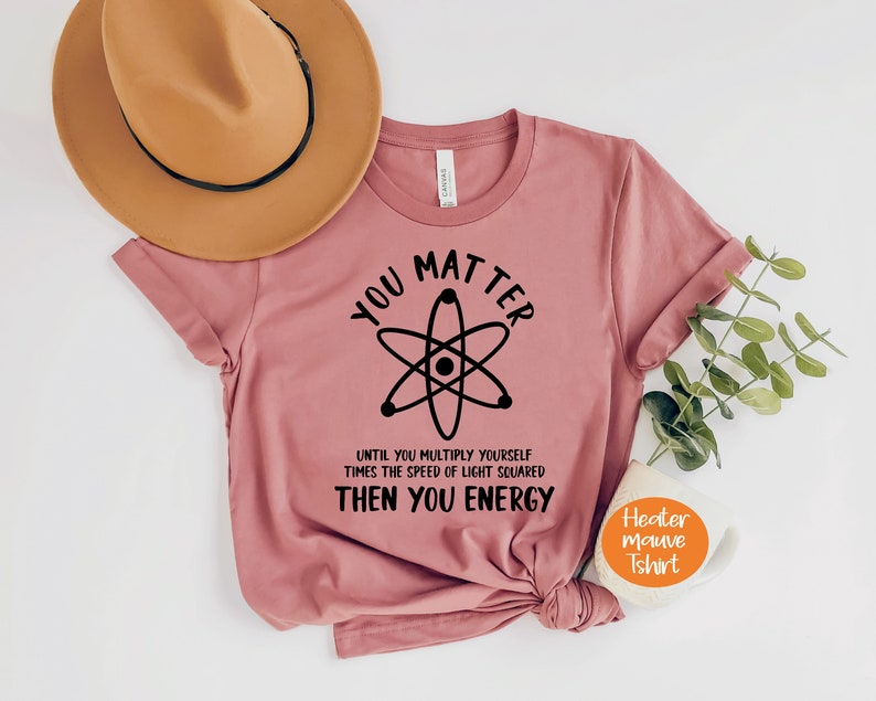 May include: A heather mauve t-shirt with a black atom graphic and the text "You Matter Until You Multiply Yourself Times The Speed Of Light Squared Then You Energy".