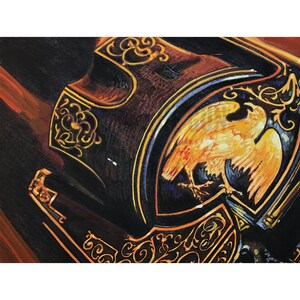 May include: A close-up of a vintage-style, ornate, black and gold musical instrument with an eagle design. The eagle is painted in shades of yellow and orange, with a dark blue background.